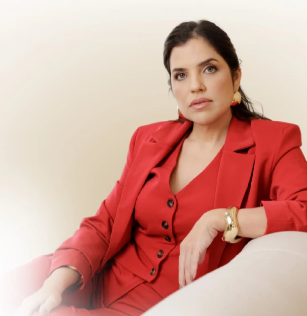 Dra. Marcella Ledo, médica dermatologista, sentada em uma poltrona clara